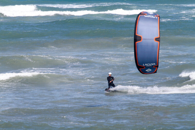 Kiteboarder riding on ocean with white helmet. Kite in the foreground