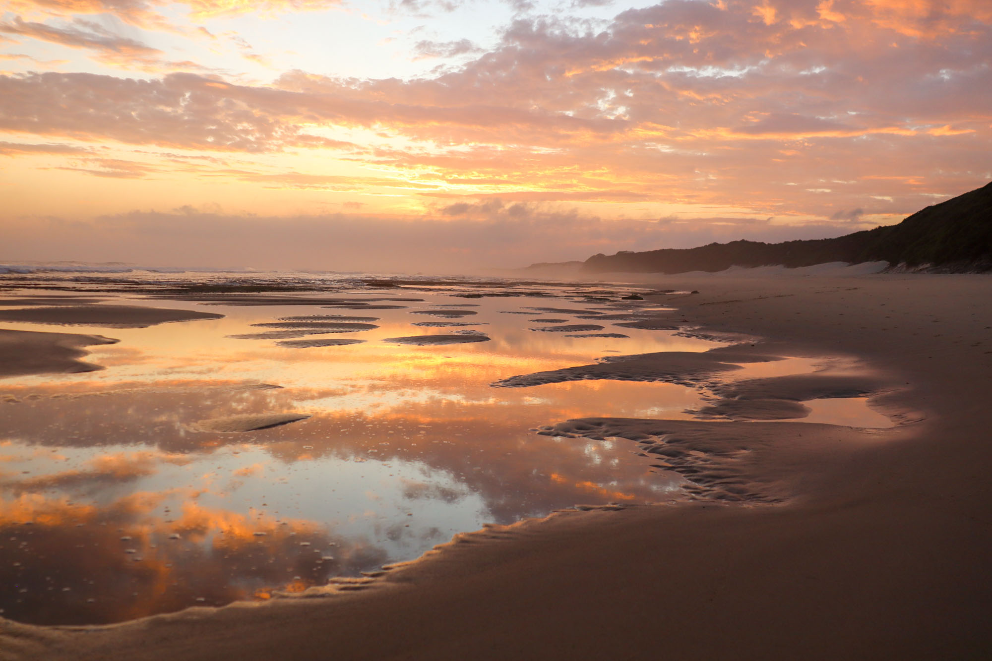 Beach at sunset with water puddles