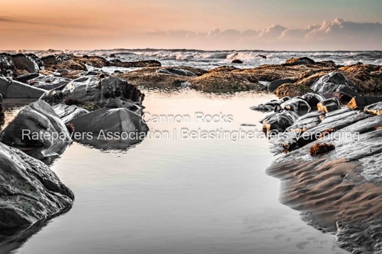 Water with rocks and a sunrise sky with writing