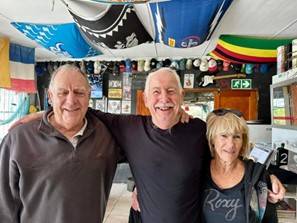 2 men and one woman in front of bar